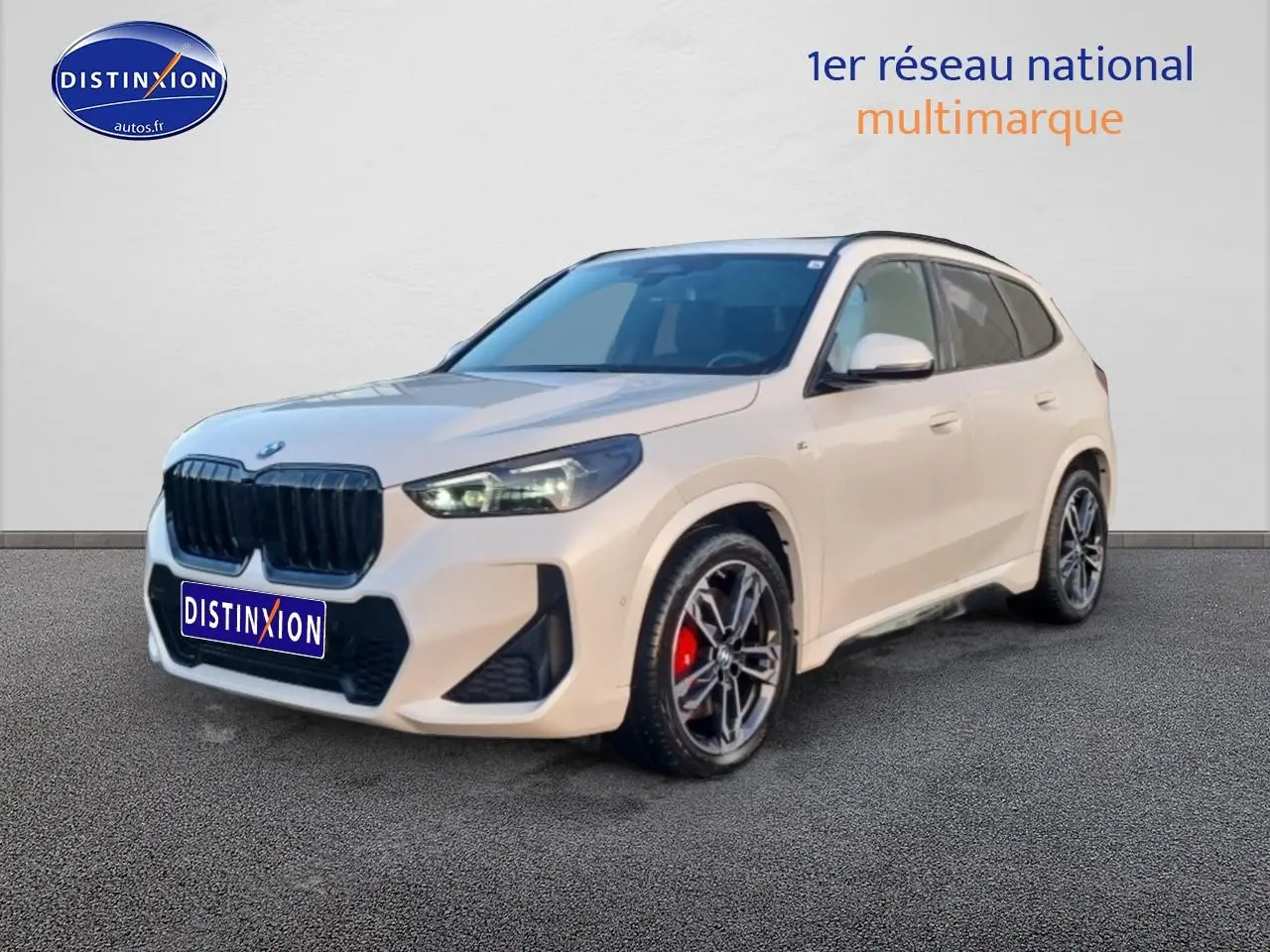 BMW X1 blanc minéral en 3/4 avant droit avec jantes alliage bicolores et étriers de frein rouges visibles