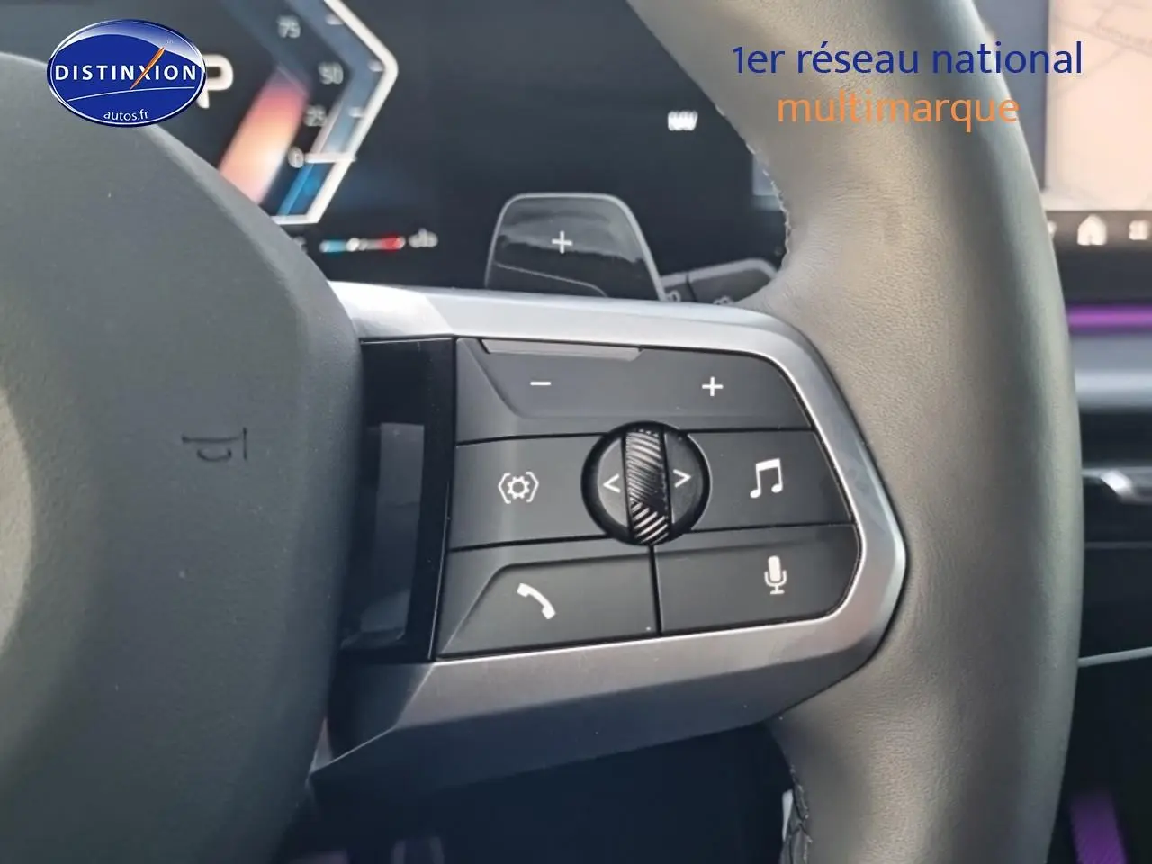 Gros plan sur les commandes multifonctions du volant cuir de la BMW X1 2025, avec éclairage d'ambiance violet en arrière-plan.