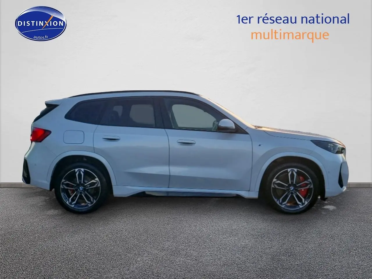 BMW X1 blanc minéral en vue de profil côté gauche, avec jantes alliage M bicolores et freins rouges visibles.