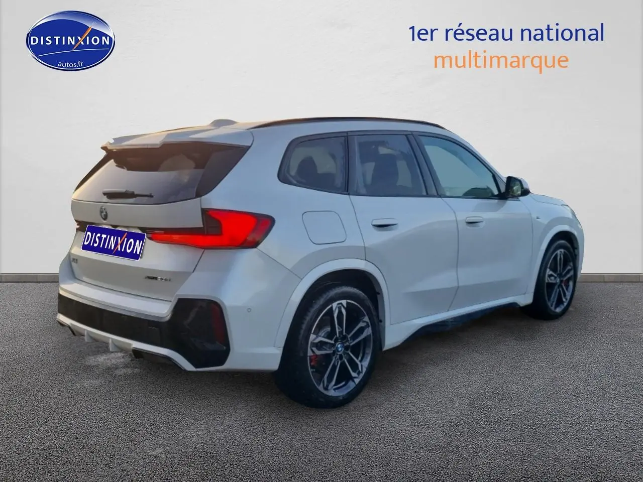 BMW X1 blanc minéral vue 3/4 arrière droit avec jantes alliage M bicolores et éléments M sport visibles.