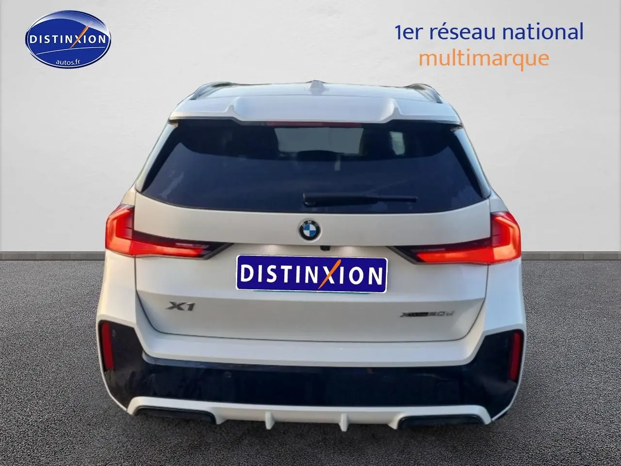 Vue arrière d’un BMW X1 blanc minéral avec feux LED et logo distinctif sur fond neutre.