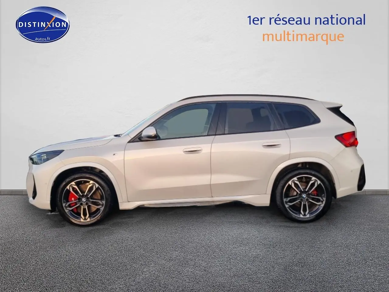 Profil gauche d’un BMW X1 blanc minéral avec jantes alliage bicolores et étriers de frein rouges.