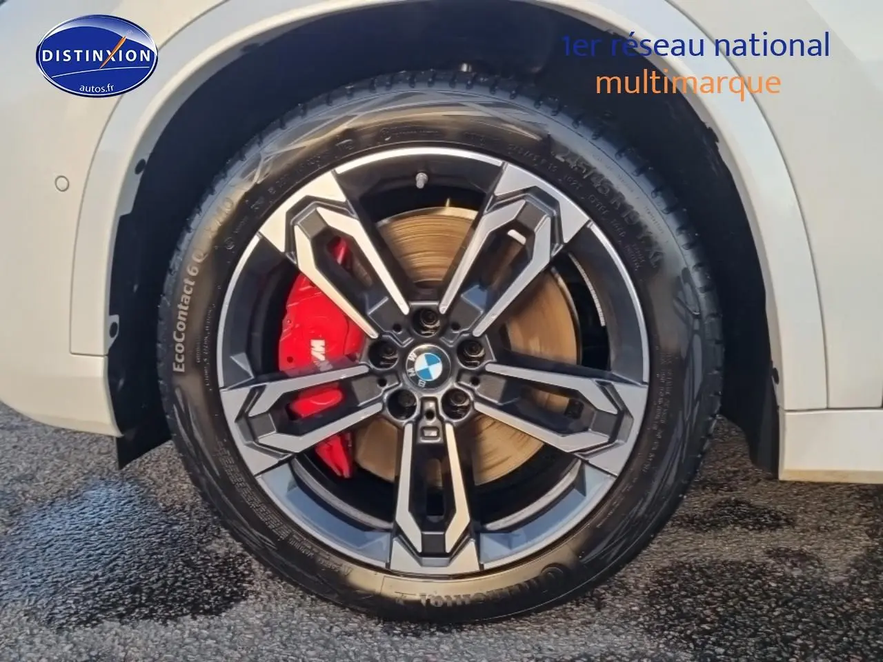 Gros plan sur la roue avant droite blanche d'une BMW X1 2025 avec jante alliage bicolore et étrier de frein rouge.