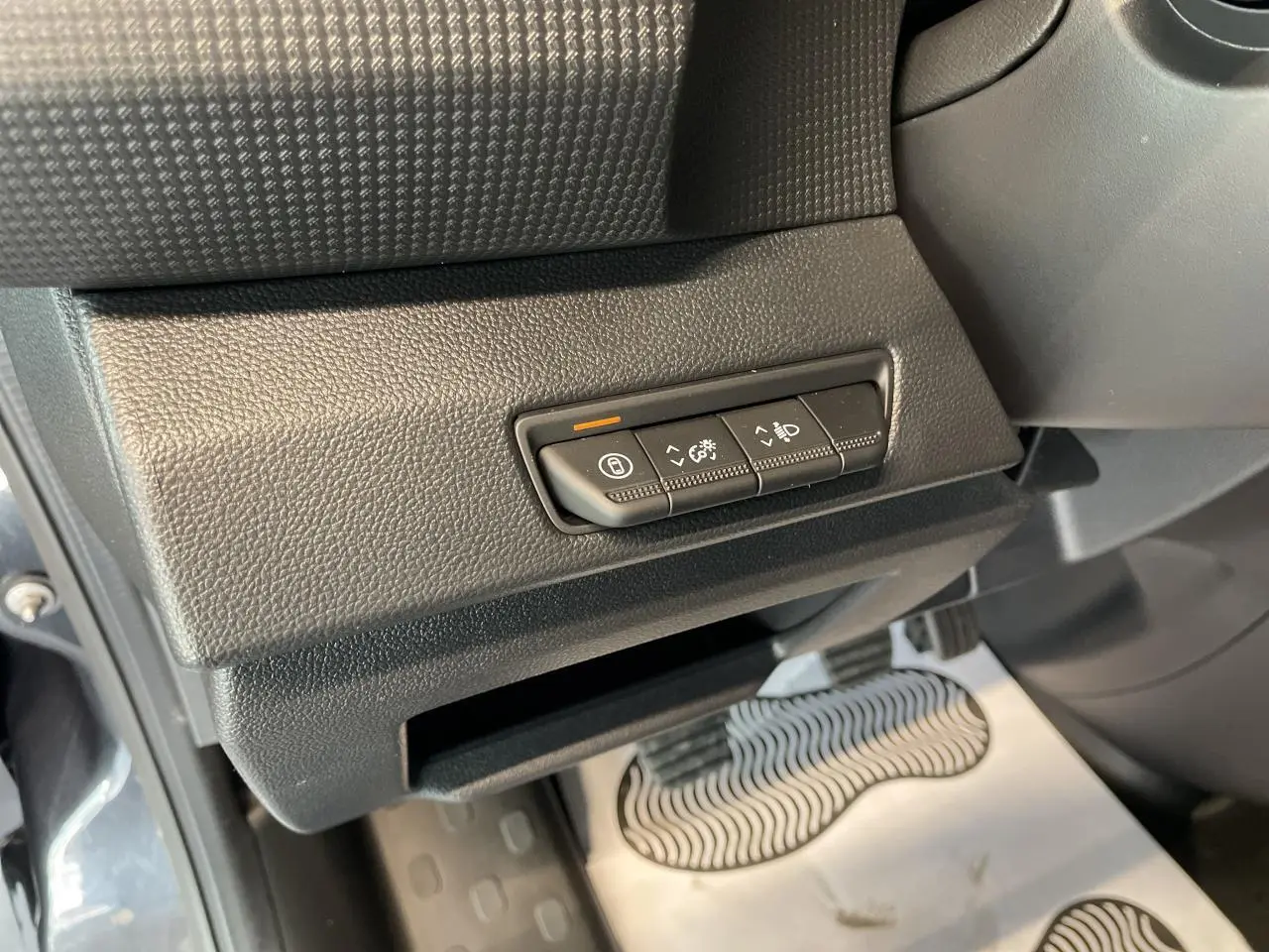 Gros plan sur les commandes de réglage des phares et du tableau de bord, intérieur noir du Renault Trafic Fourgon gris Comète.