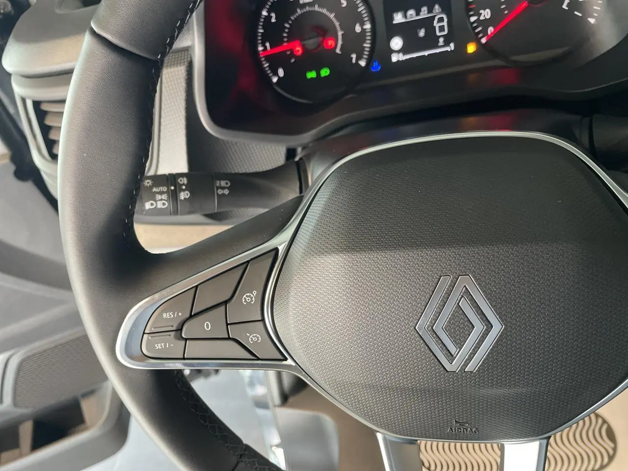 Gros plan sur le volant noir du Renault Trafic Fourgon 2025 avec commandes intégrées et tableau de bord lumineux en arrière-plan.