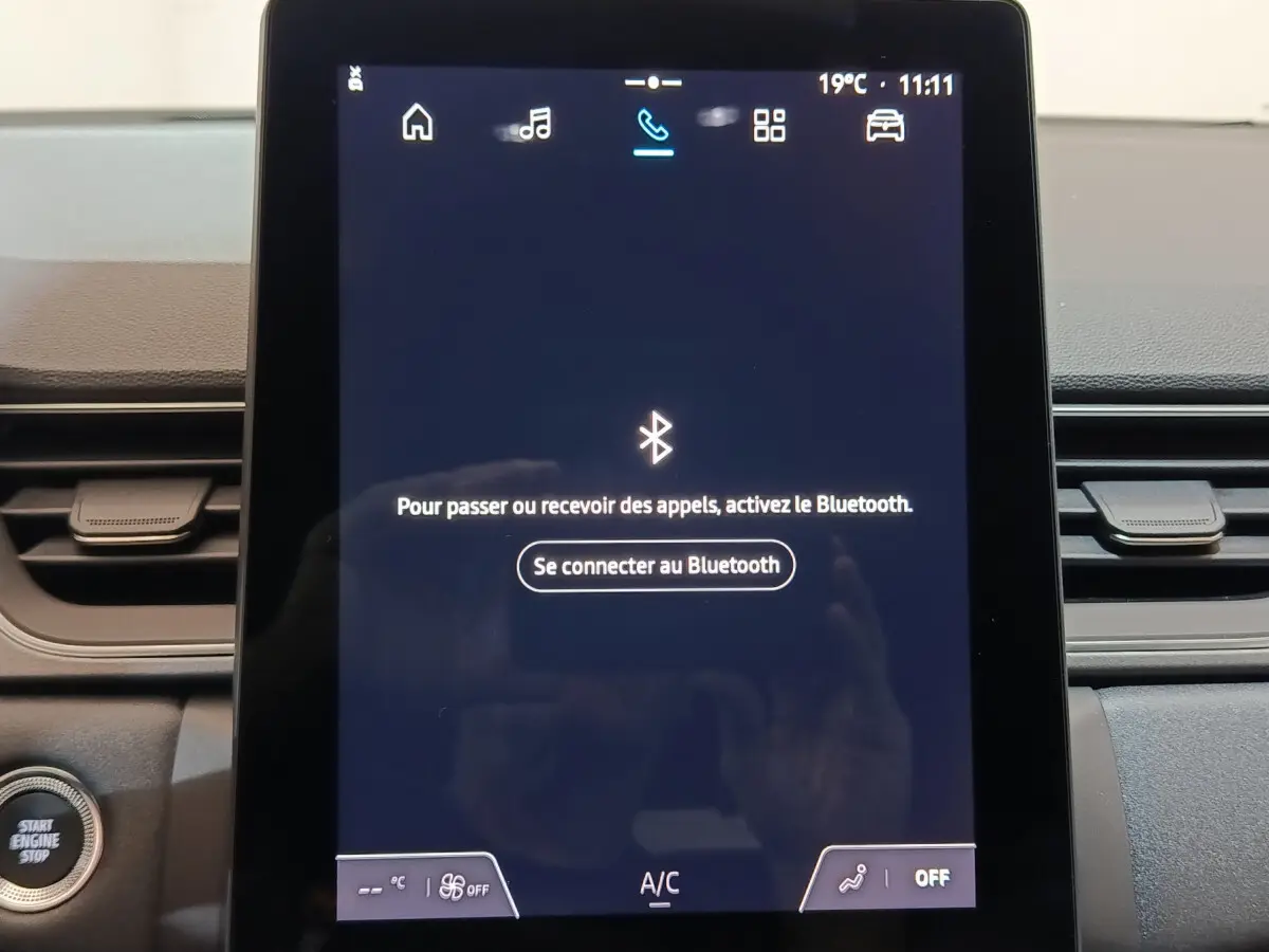 Écran tactile central allumé du tableau de bord du Renault Captur blanc, avec bouton démarrage visible à gauche.