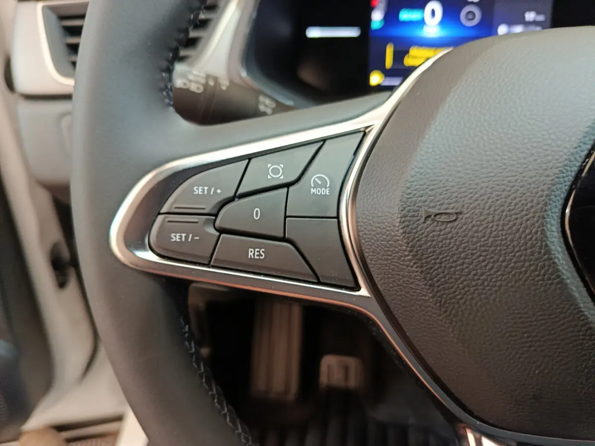 Gros plan sur le côté gauche du volant cuir du Renault Captur blanc 2025, avec commandes multifonctions visibles.