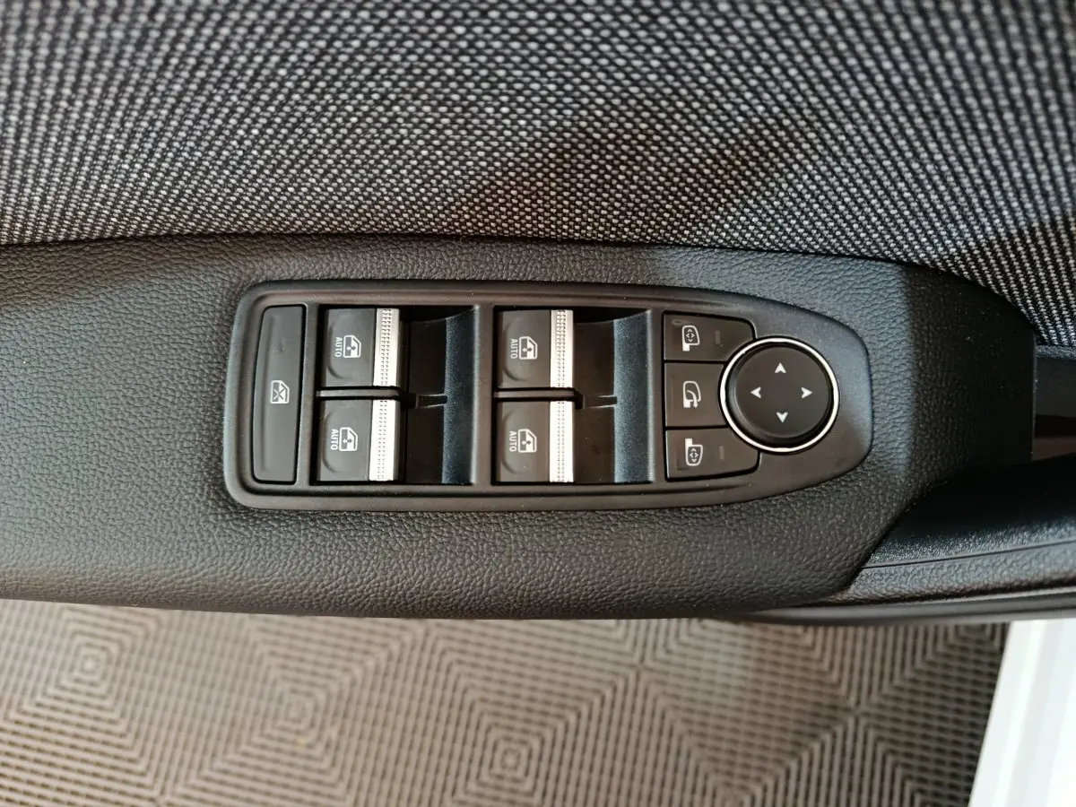 Gros plan sur les commandes de lève-vitres et rétroviseurs côté conducteur du Renault Captur blanc 2025.