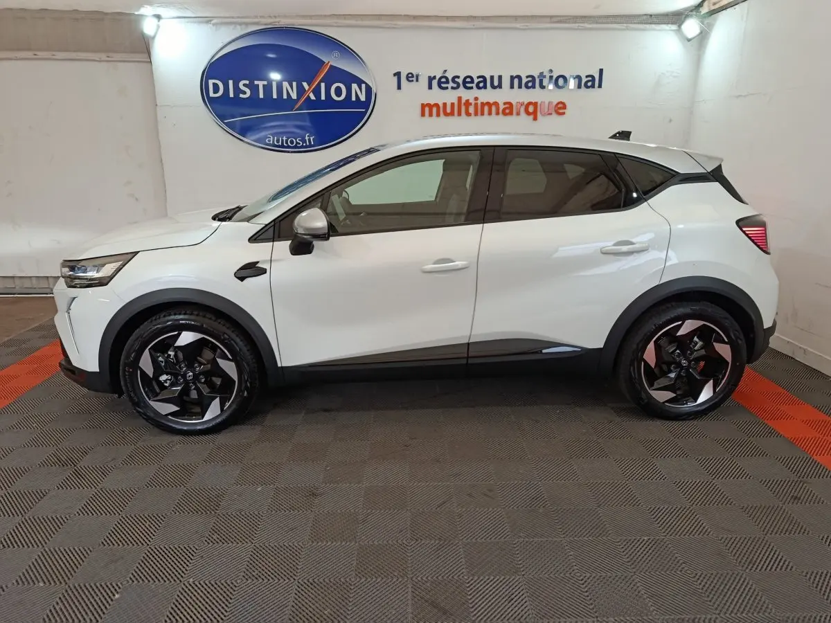 Profil latéral gauche d'un Renault Captur blanc 2025 en version techno E-Tech full hybrid, roues noires à jantes stylisées.
