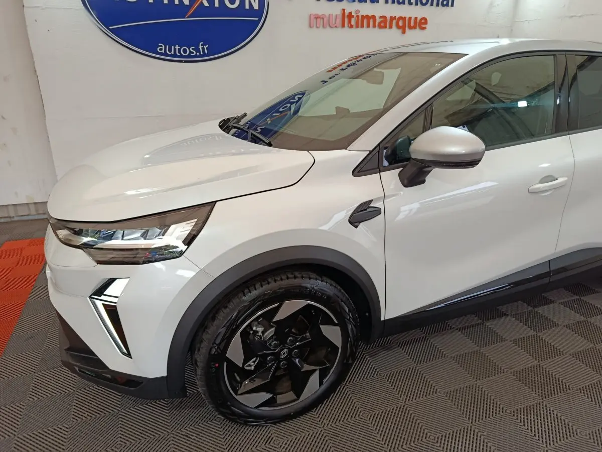Vue 3/4 avant droit du Renault Captur blanc 2025 avec jantes noires et phares LED distinctifs.