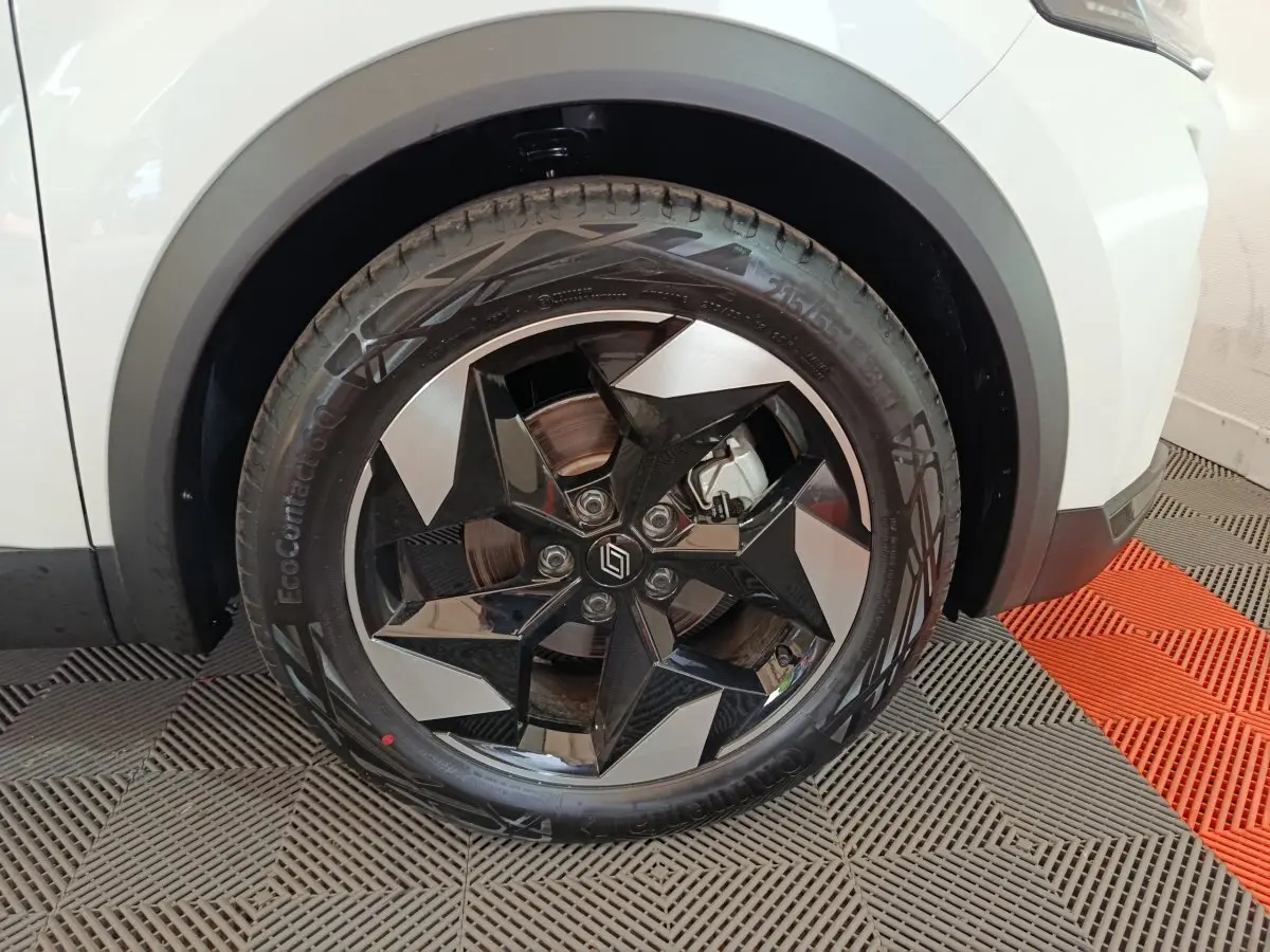 Gros plan sur la roue avant droite du Renault Captur blanc 2025, mettant en valeur la jante noire et argentée au design géométrique.