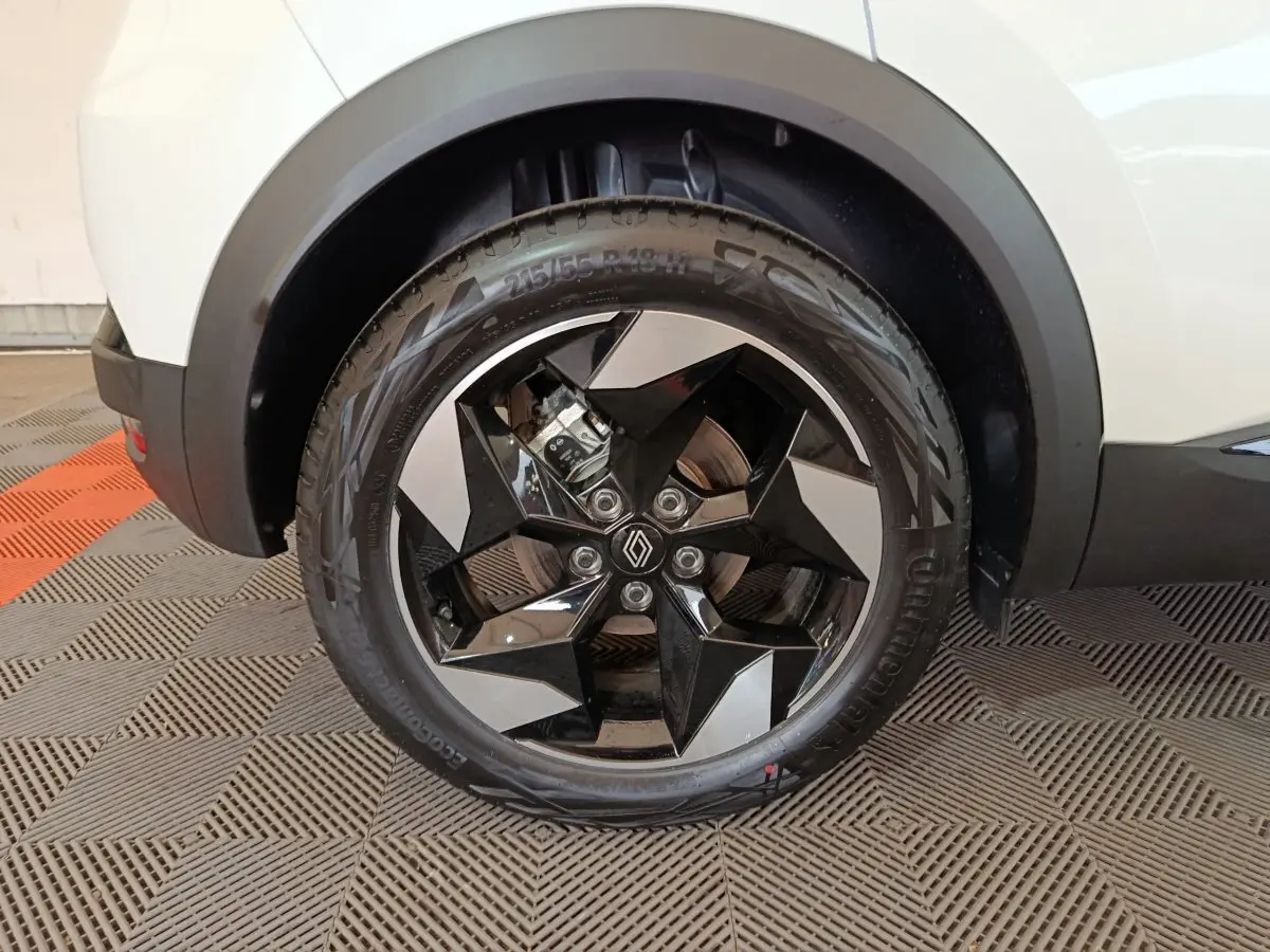 Gros plan sur la roue avant droite du Renault Captur blanc 2025 avec jante noire et argent au design géométrique.