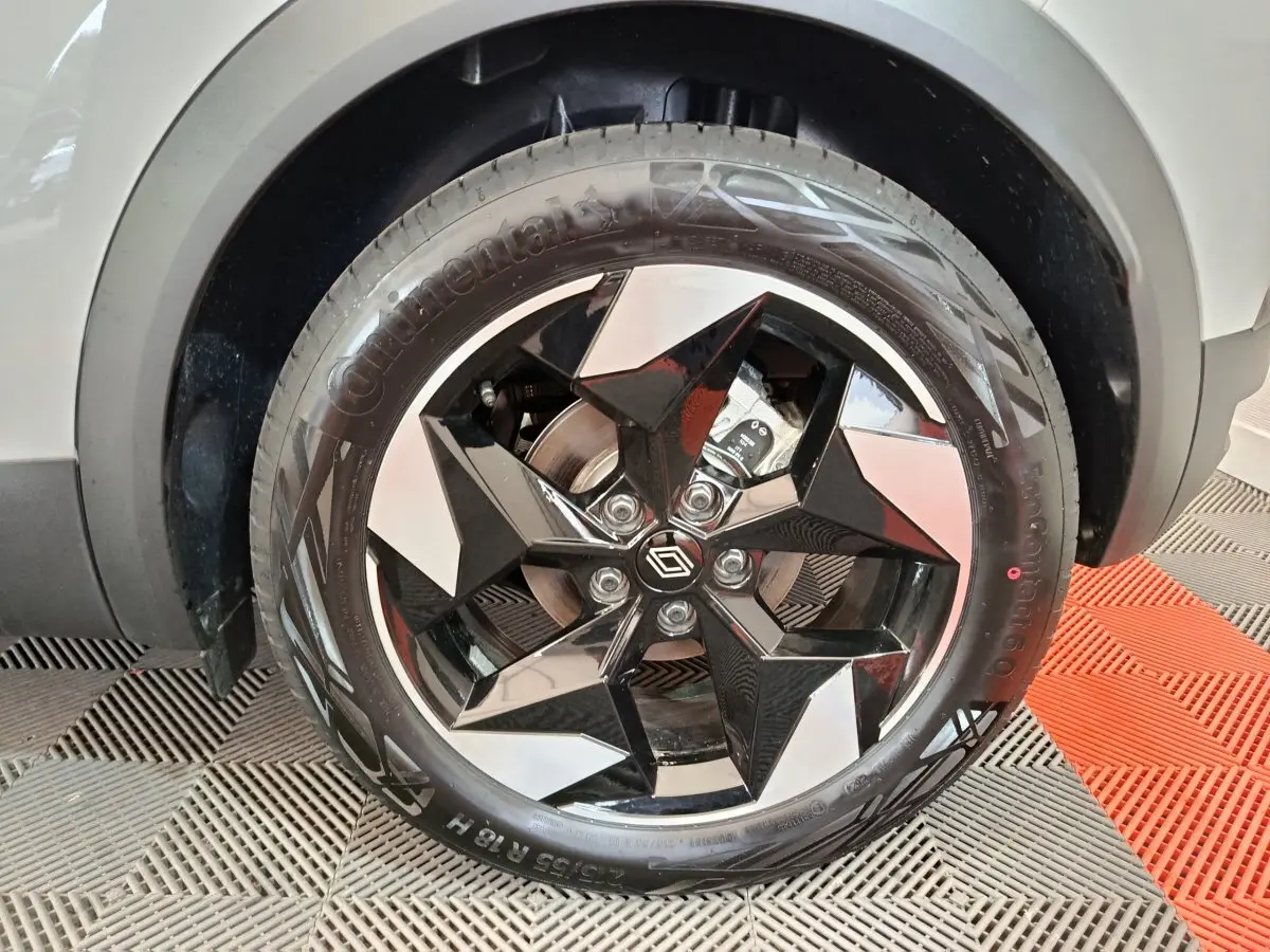 Gros plan sur la roue avant droite du Renault Captur blanc 2025 avec jante noire et argentée au design géométrique.