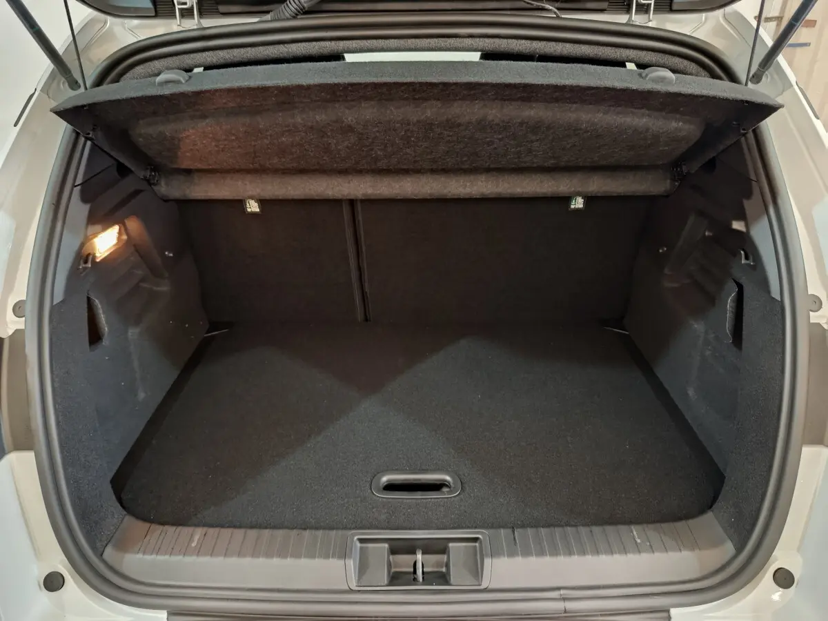 Coffre ouvert vu de l'arrière d'un Renault Captur blanc, montrant un espace de chargement propre et vide.