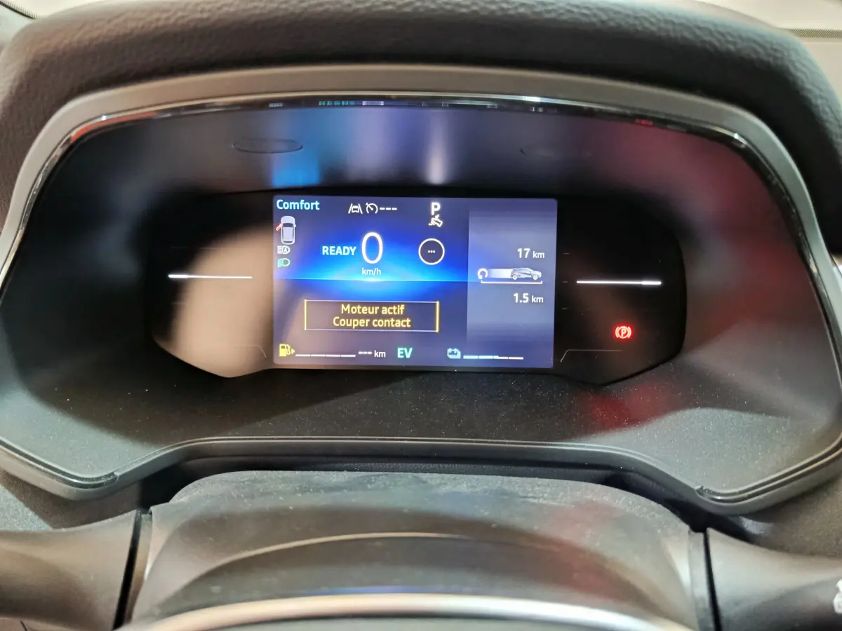 Gros plan sur le combiné d'instruments numérique du Renault Captur Techno E-Tech blanc, affichant 0 km/h et alertes moteur.