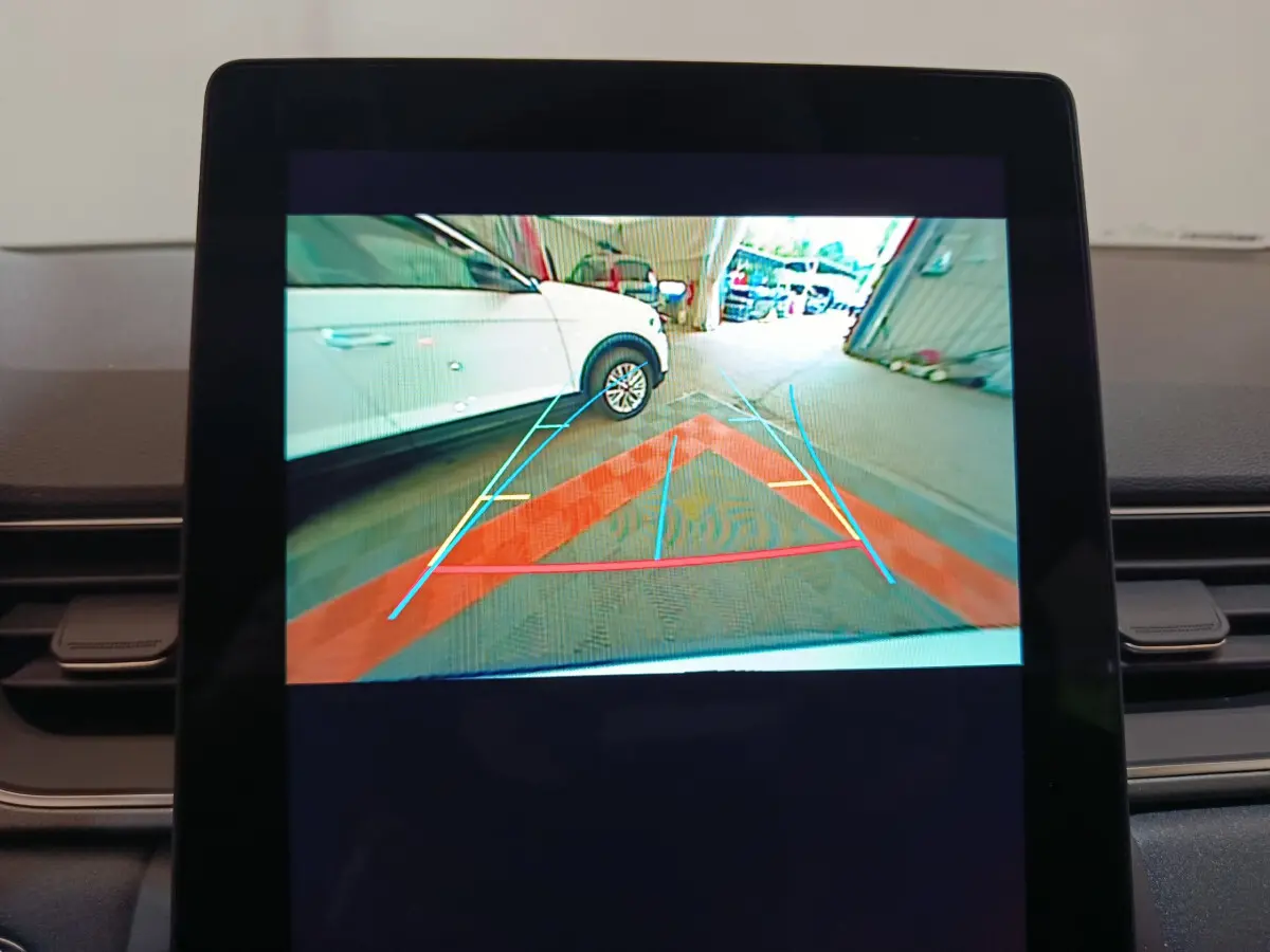 Affichage caméra de recul montrant un Renault Captur blanc en 3/4 arrière droit avec lignes de guidage colorées.