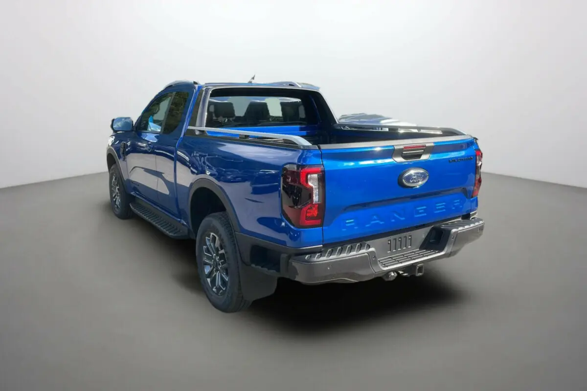 Vue 3/4 arrière droite du Ford Ranger Wildtrak bleu lightning avec arceau sport et attelage visible.