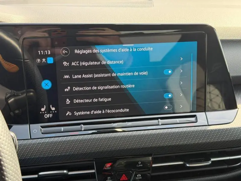 Écran tactile central du tableau de bord de la Volkswagen Golf 2024 affichant les réglages d'aides à la conduite.