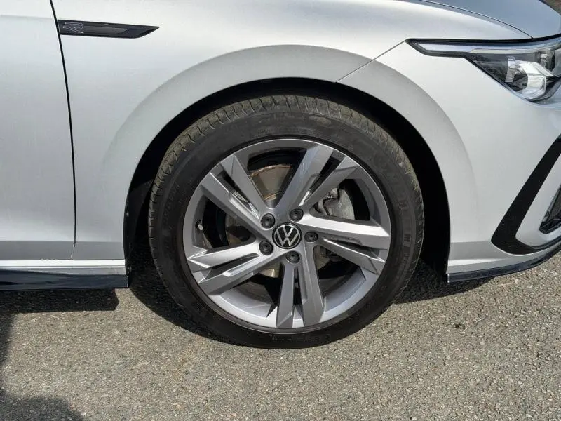 Gros plan sur la roue avant gauche d'une Volkswagen Golf 2024 R-Line en Reflet d'Argent métallisée avec jante alliage distinctive.