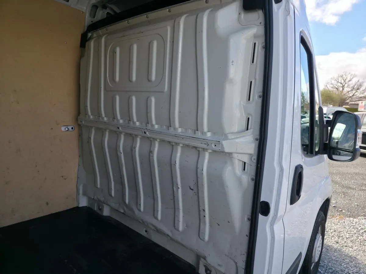 Vue intérieure arrière du fourgon blanc Opel Movano 2022, montrant la cloison pleine tôlée et le plancher noir.