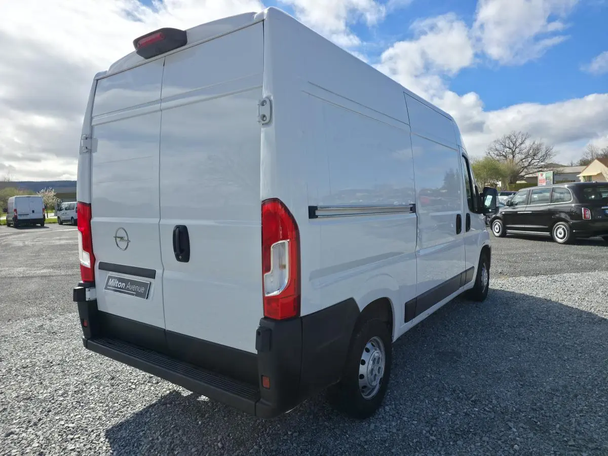Vue 3/4 arrière droite d’un Opel Movano Fourgon blanc avec portes battantes arrière et porte latérale coulissante.
