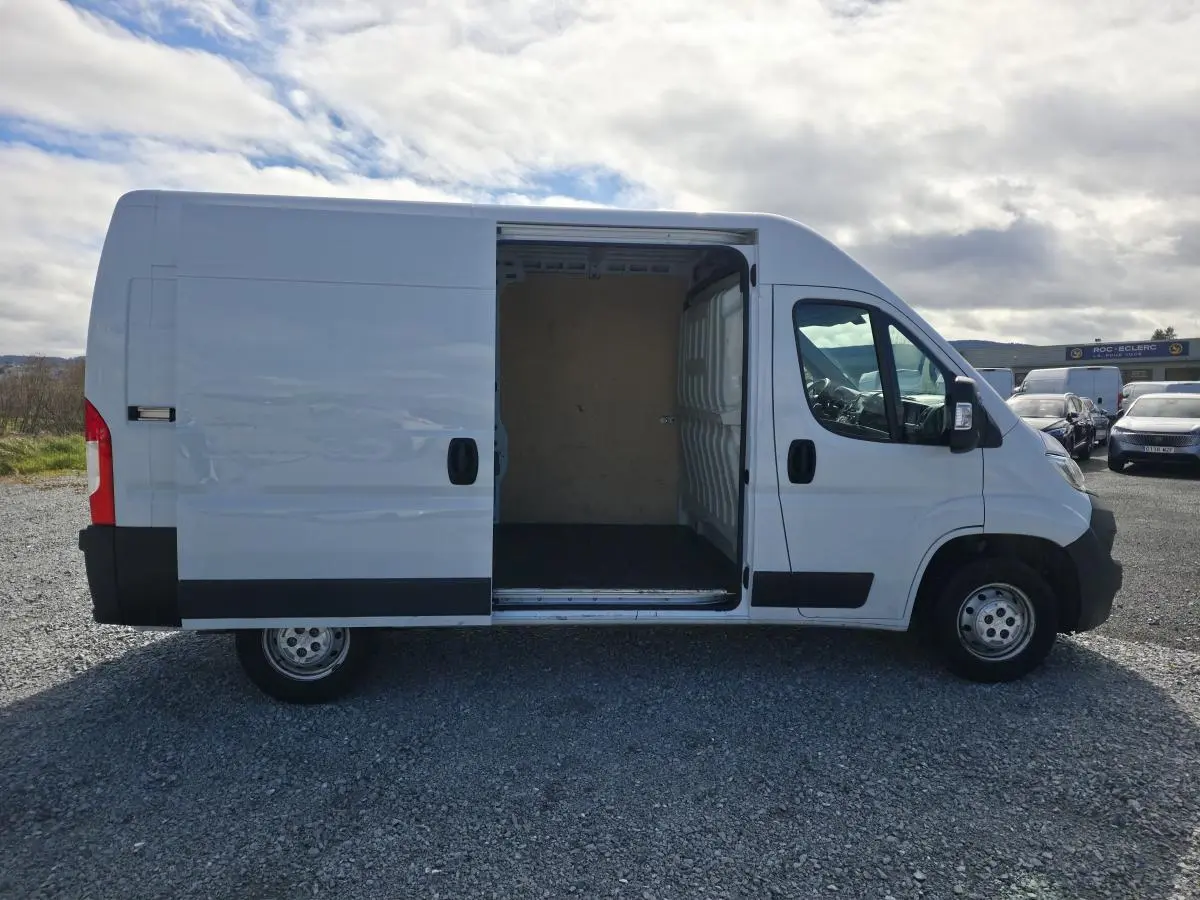 Opel Movano Fourgon blanc vue de profil droit avec porte latérale coulissante ouverte montrant l’espace de chargement.