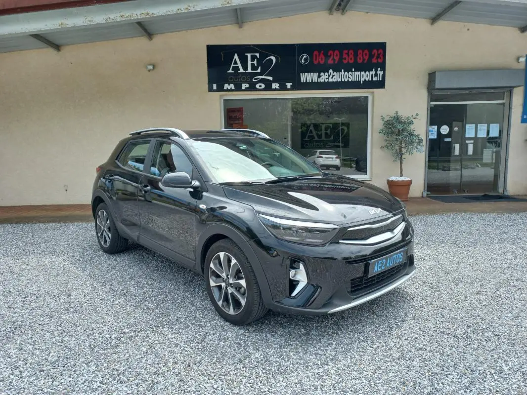 KIA STONIC noir 2025 en 3/4 avant droit, avec jantes alliage et toit ouvrant visible, stationné devant un garage.