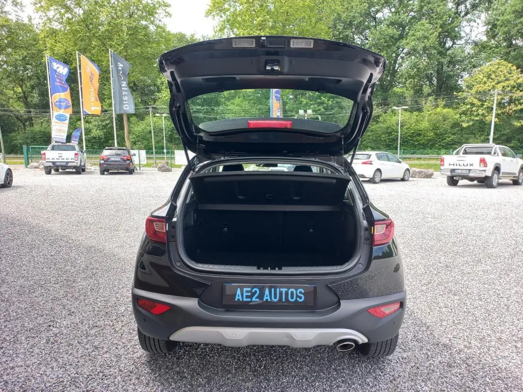 Vue arrière d’un KIA STONIC noir 2025 avec coffre ouvert, mettant en valeur son hayon et son pare-chocs gris.