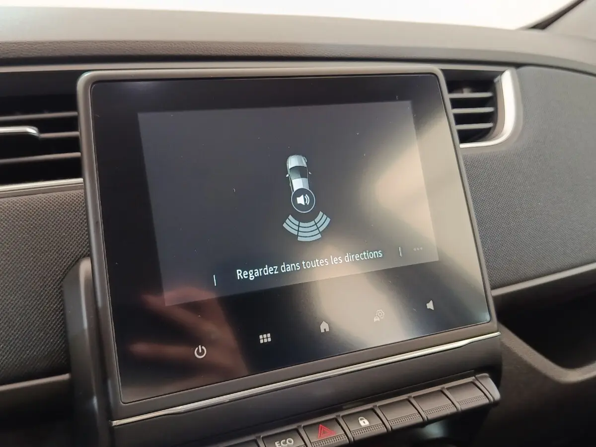 Écran tactile central de la Renault ZOE blanche 2021 affichant l'aide au stationnement intérieur.