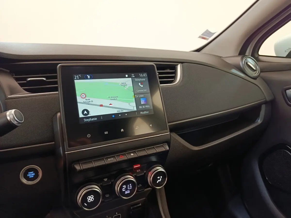 Vue intérieure côté passager du tableau de bord noir de la Renault ZOE 2021 avec écran tactile de navigation allumé.
