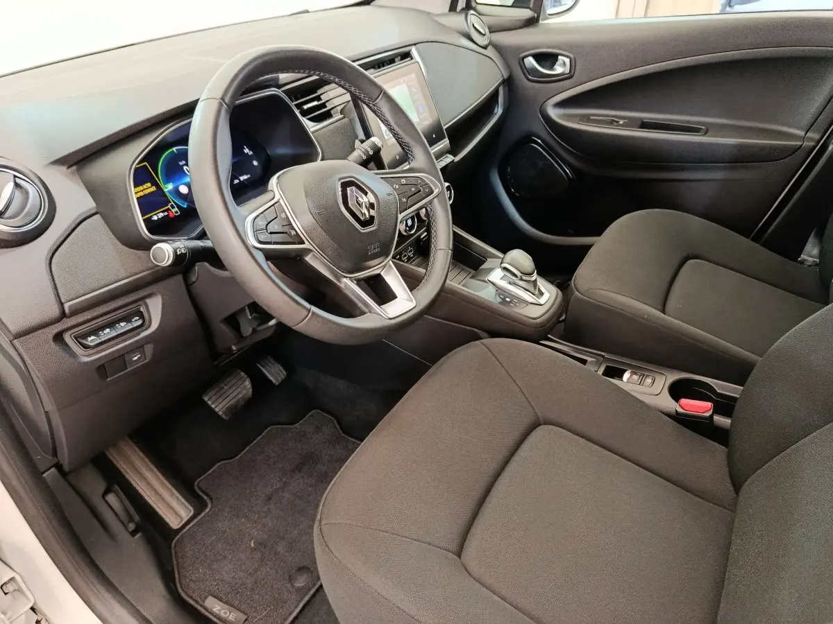 Vue intérieure côté conducteur de la Renault ZOE 2021, volant multifonctions cuir synthétique et écran tactile central visible.