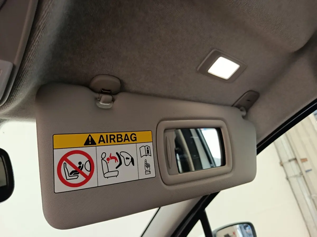 Détail du pare-soleil côté conducteur avec miroir et avertissement airbag dans une Renault ZOE blanche 2021.