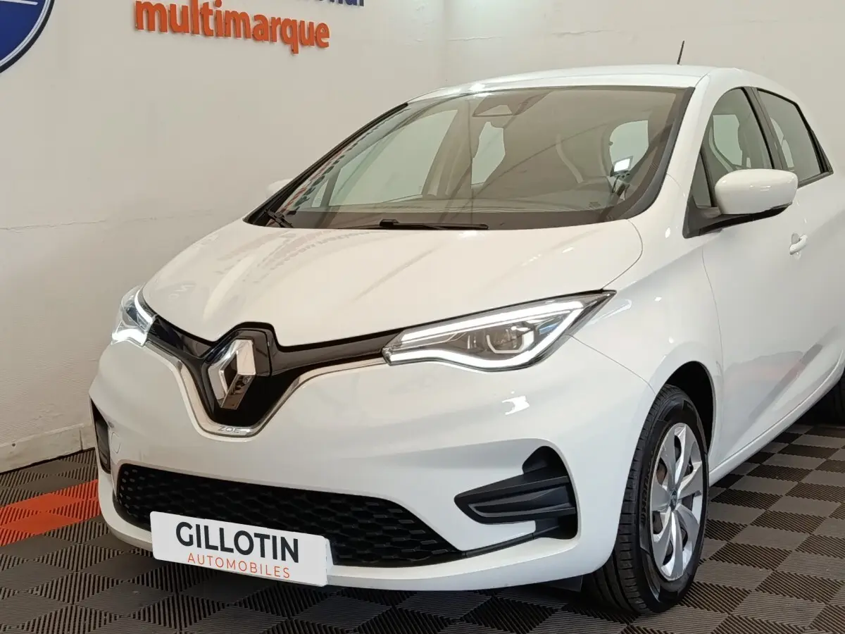 Vue 3/4 avant d'une Renault ZOE Business Rev R110 blanche, avec phares LED et calandre noire brillante.