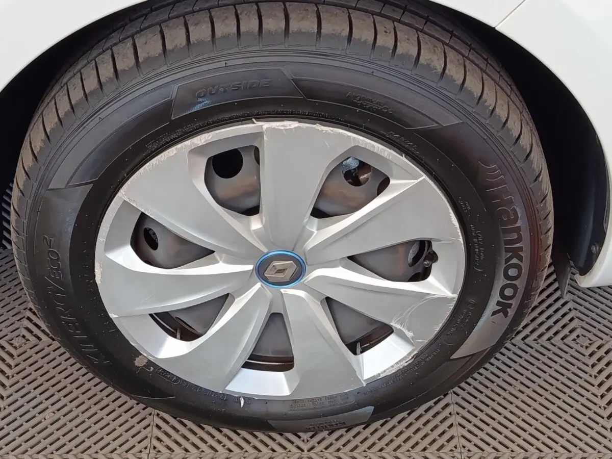 Gros plan sur la roue avant droite blanche d'une Renault ZOE 2021 avec jante abîmée et logo Renault central.