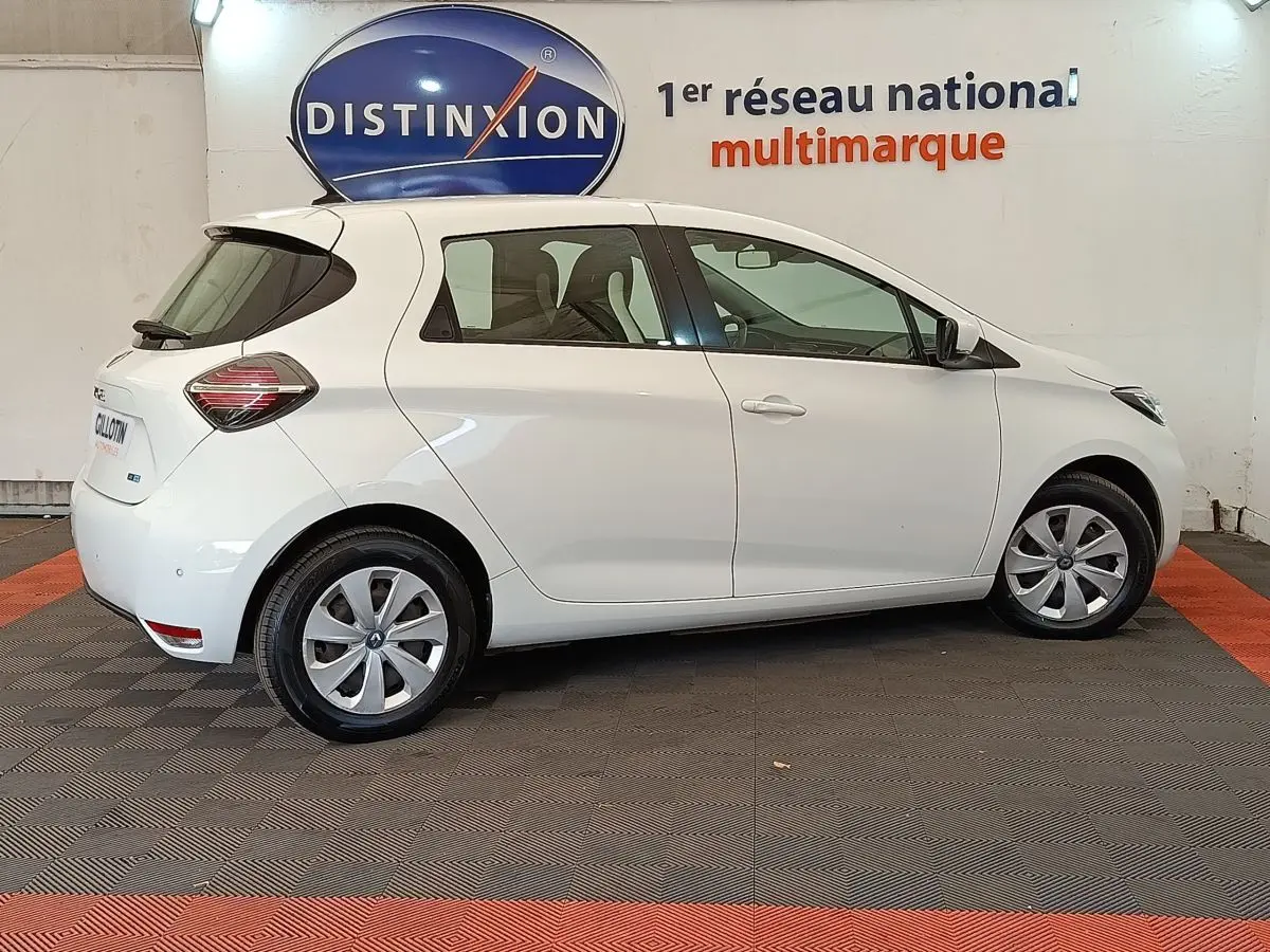Profil droit d'une Renault ZOE Business Rev R110 blanche de 2021, avec jantes et feux arrière distinctifs visibles.
