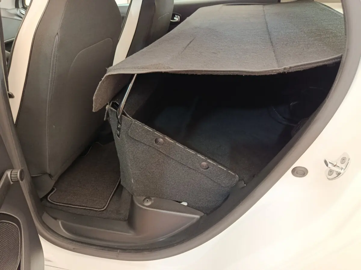 Vue intérieure côté arrière droit de la Renault ZOE blanche 2021, montrant le coffre partiellement ouvert et la banquette arrière.