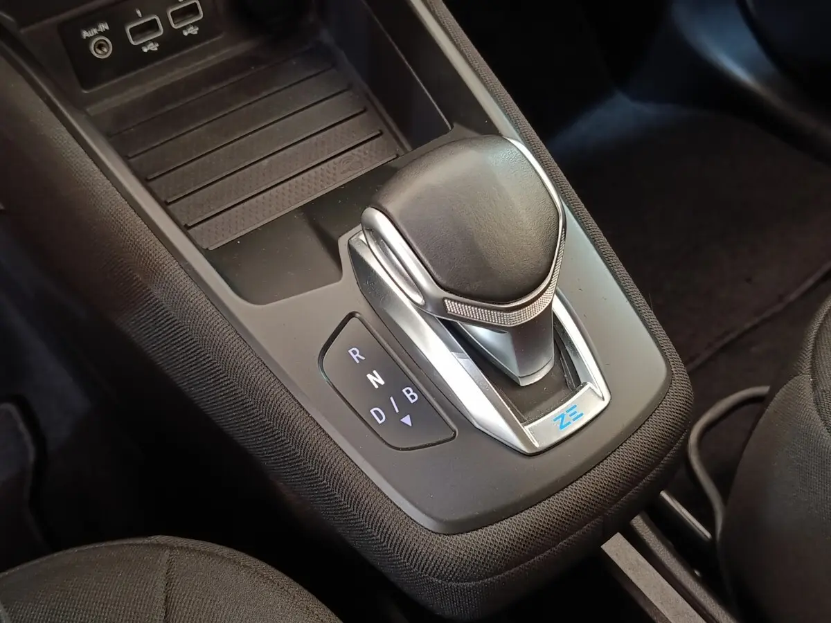 Gros plan sur la commande de boîte automatique noire avec logo ZE dans l’habitacle de la Renault ZOE blanche.