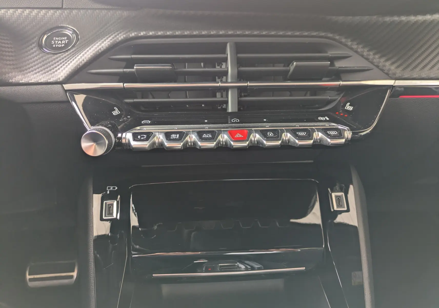 Vue rapprochée de la console centrale noire brillante du Peugeot 208 Hybrid 145, avec commandes tactiles et bouton start/stop.
