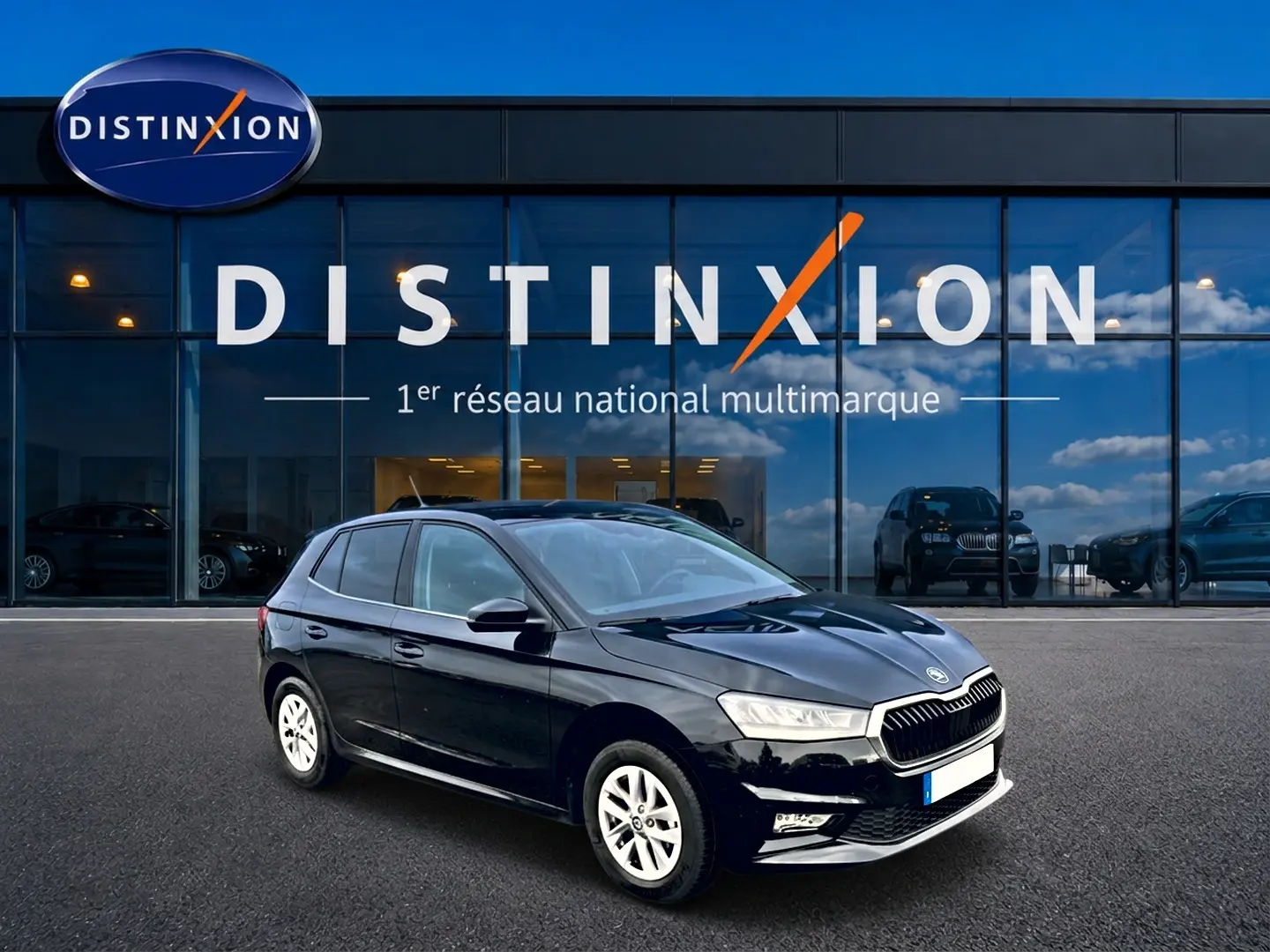 Vue 3/4 avant droite d'une Skoda Fabia noire garée devant une vitrine avec logo Distinxion.
