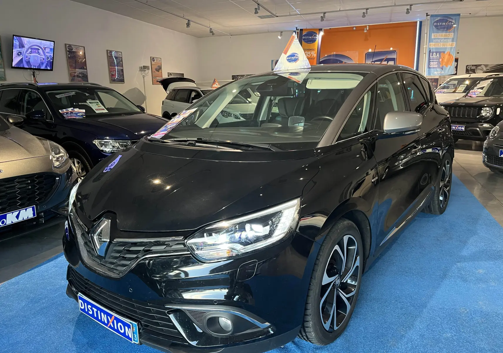 Renault Scenic IV noir étoile métal avec toit gris, vue 3/4 avant droit en showroom lumineux.