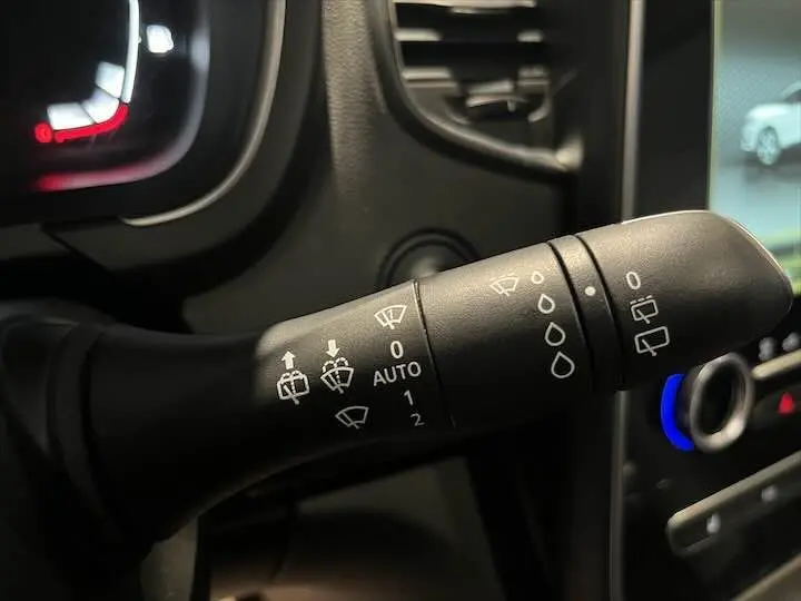 Gros plan sur la commande des essuie-glaces du Renault Scenic IV noir étoile métal avec tableau de bord et écran tactile en arrière-plan.