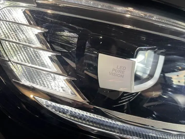 Gros plan sur le phare avant gauche LED Pure Vision du Renault Scenic IV noir étoile métal avec toit gris.