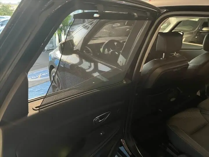 Vue intérieure côté arrière gauche du Renault Scénic IV noir étoile métal avec pare-soleil en filet sur la porte ouverte.