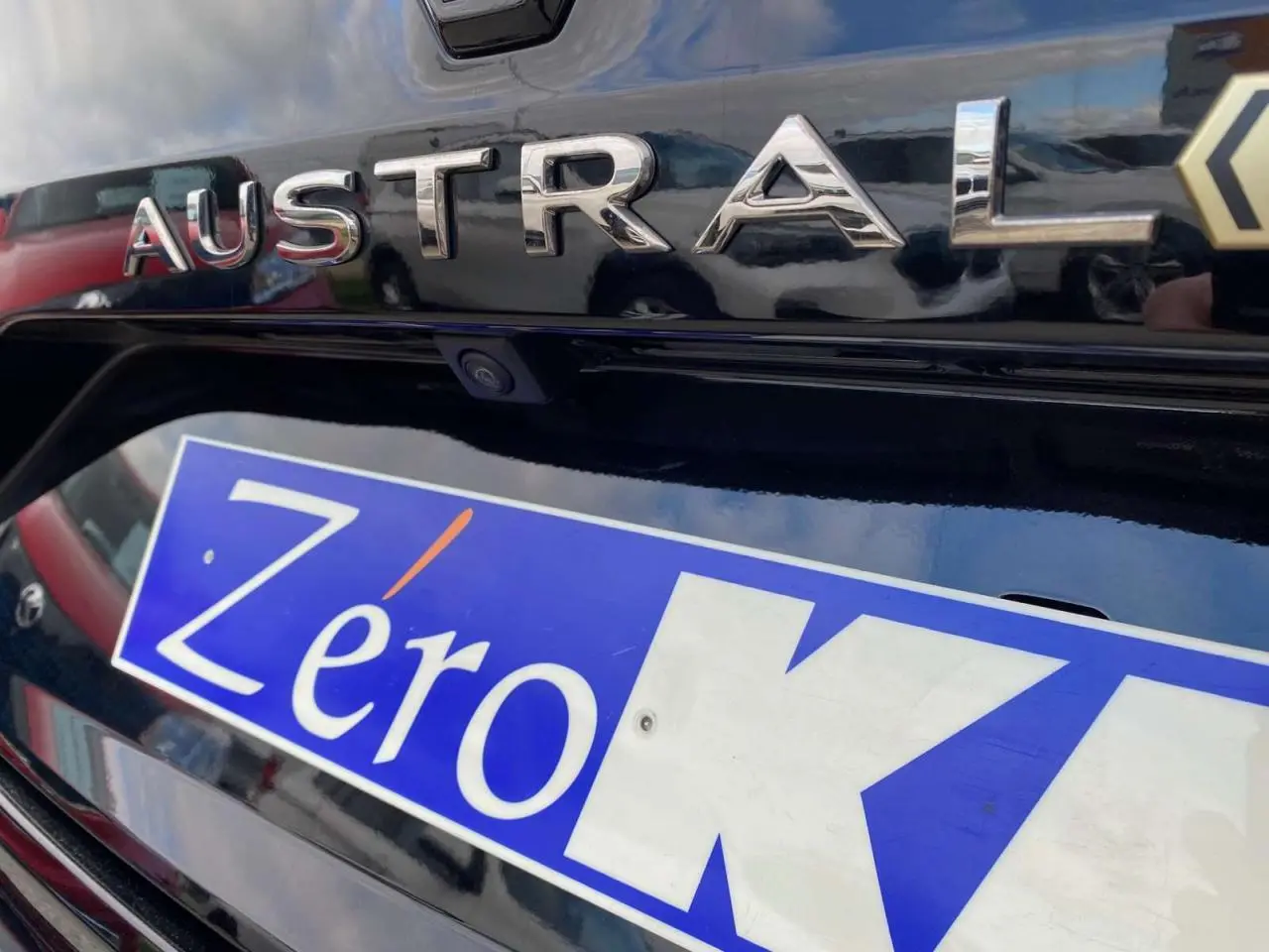 Gros plan sur le hayon arrière noir étoilé du Renault Austral E-Tech Full Hybrid avec logo et caméra de recul visible.