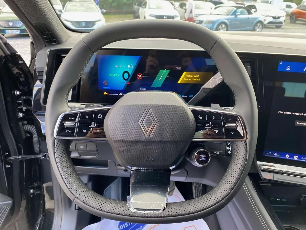 Vue intérieure du volant cuir perforé et tableau de bord numérique du Renault Austral noir étoilé 2025 E-Tech Hybrid.