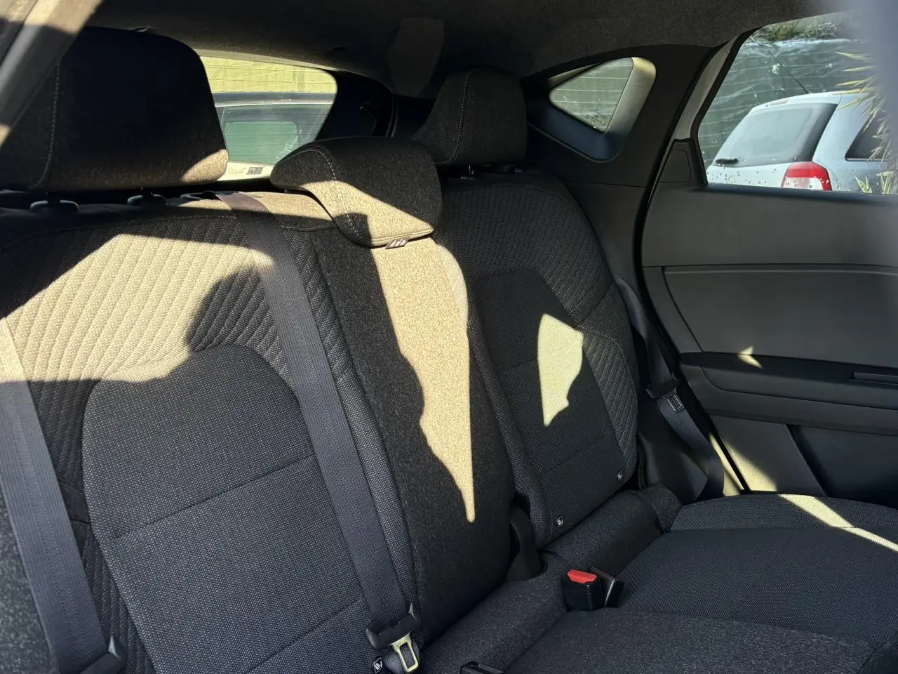 Vue intérieure côté droit des sièges arrière en tissu noir du Renault Captur 2025 hybride, avec ceinture de sécurité visible.