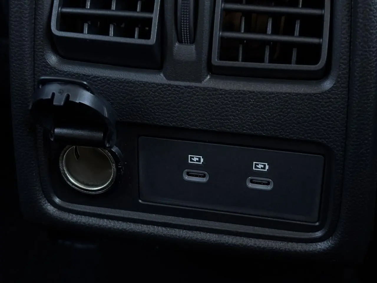 Prise USB double et allume-cigare noir en gros plan sur la console arrière du Renault Captur gris Rafale.