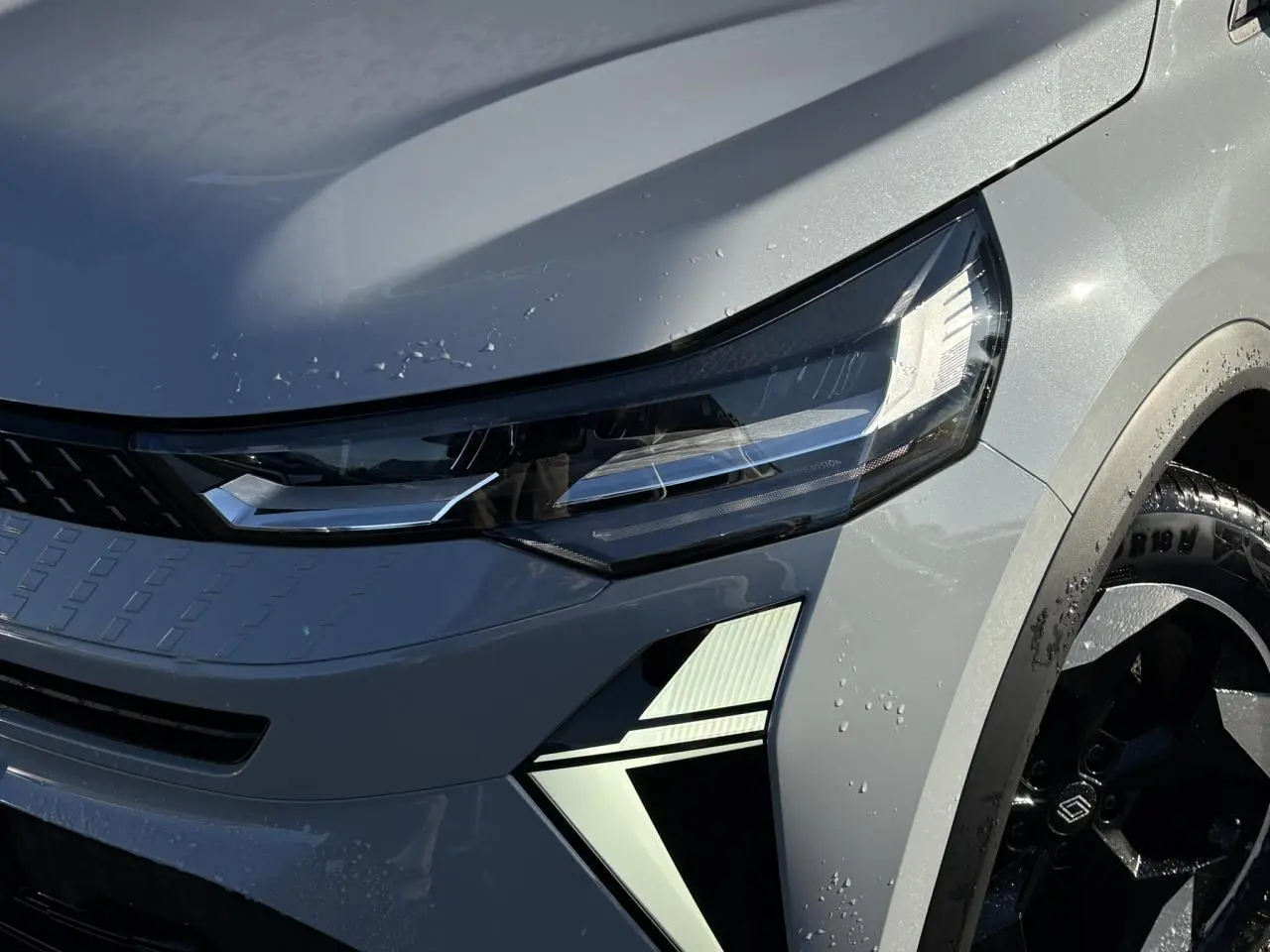 Gros plan sur l'avant droit du Renault Captur gris Rafale, mettant en valeur le phare LED et la jante aluminium noire.