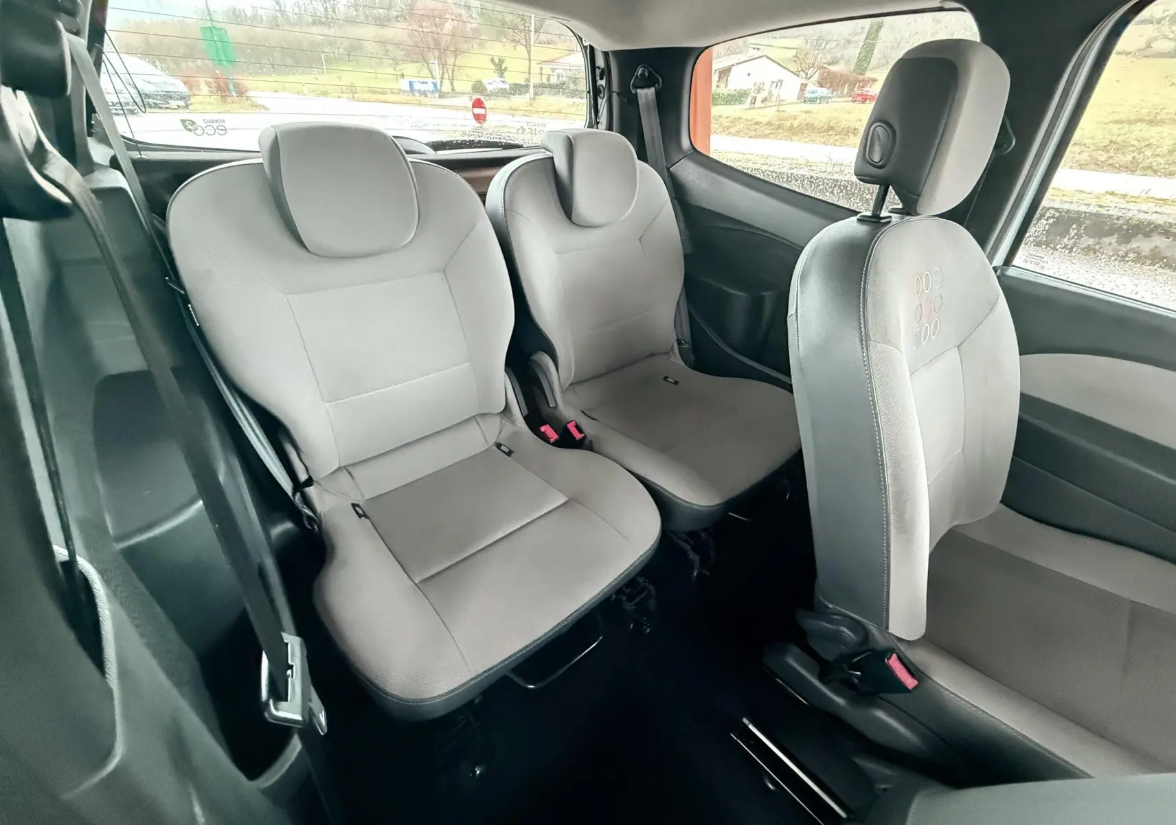 Vue intérieure arrière montrant les sièges gris en tissu de la Renault Twingo II 2009, côté gauche et droit visibles.