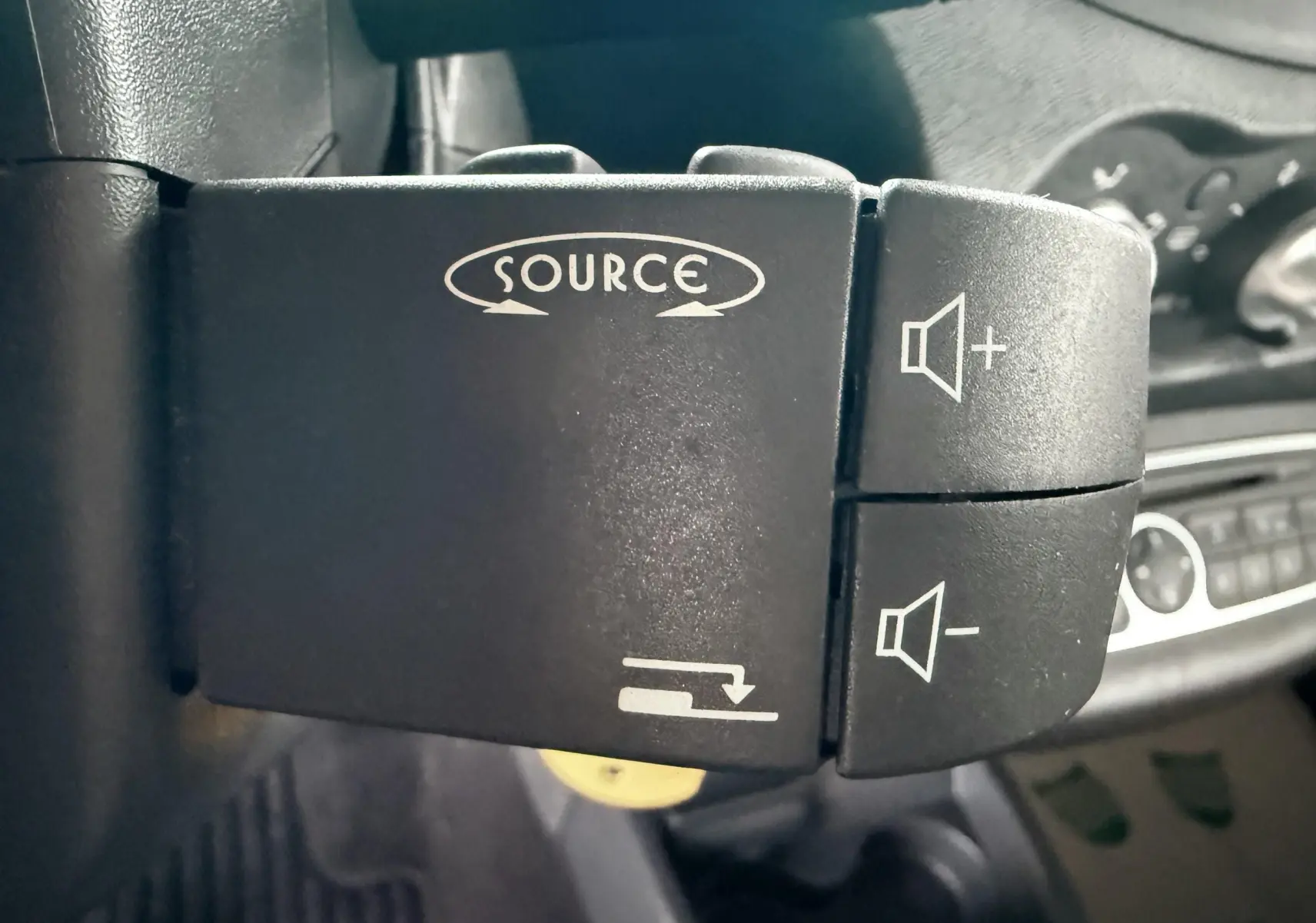 Gros plan sur les commandes audio au volant d’une Renault Twingo II grise, intérieur tissu gris.